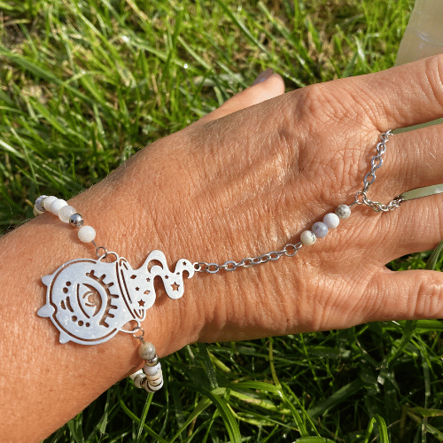 Bracelet (bijoux de main composé d'un bracelet qui s'accroche également sur le majeur) sur le thème Halloween avec une breloque argent représentant un chaudron magique, composé de merlinite - vue de face