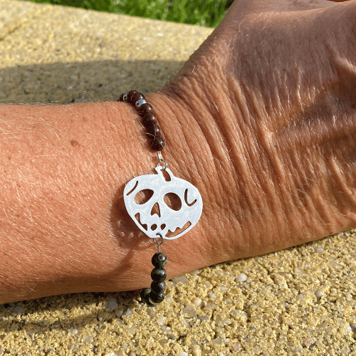 Bracelet sur le thème Halloween avec une breloque argent représentant la pomme empoissonnée de Blanche Neige, composé de grenat et jaspe kambaba - vue de face