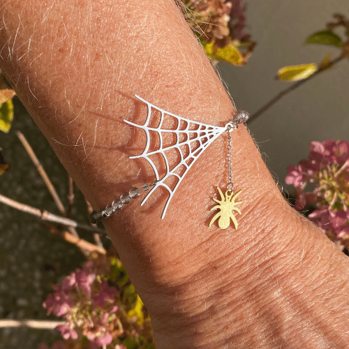 Bracelet sur le thème Halloween avec 2 breloques représentant une toile d'araignée argent sur laquelle une petite araignée dorée est attachée, composé de quartz fumé - vue de face