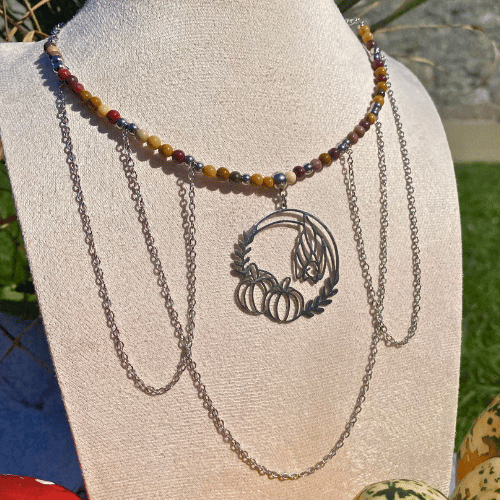 Collier sur le thème Halloween avec une breloque ronde représentant une chauve-souris qui dort à côté de citrouilles, composé de jaspe mokaïte - vue de face