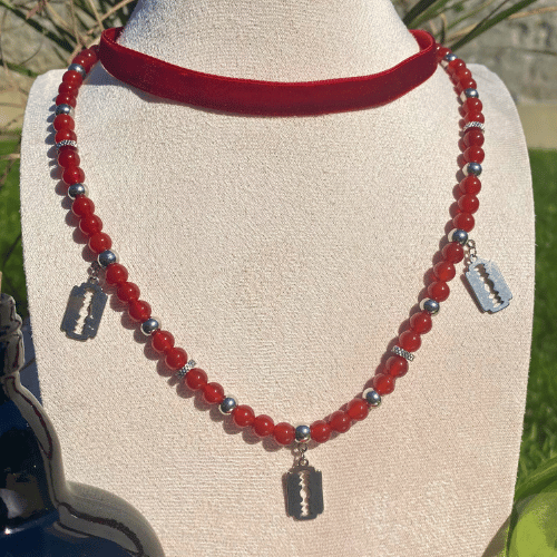 Collier sur le thème Halloween avec un ras de cou en velours rouge et un collier en cornaline avec des breloques lames de rasoir - vue de face