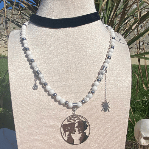 Collier sur le thème Halloween avec des breloques : un couple de squelette se regardant, un strass et une araignée, composé d'howlite matte - vue de face