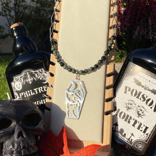 Collier sur le thème Halloween avec une breloque en forme de tombeau représentant des chauve-souris en plein vol au clair de lune, composé de jaspe kambaba - vue de face