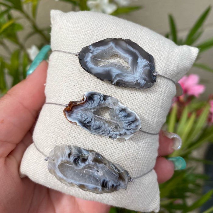 3 bracelets bohèmes sur un coussin beige avec des tranches uniques d'agate de couleur grise, monté sur fil gris, signé Les Merveilles by Pauline.
