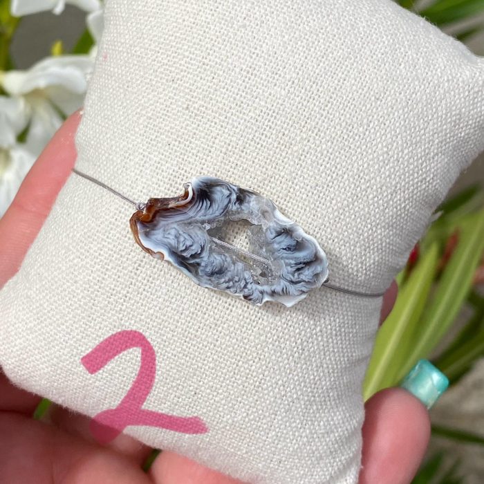 Bracelet bohème n°2 sur un coussin beige avec une tranche unique d'agate de couleur grise, monté sur fil gris, signé Les Merveilles by Pauline.