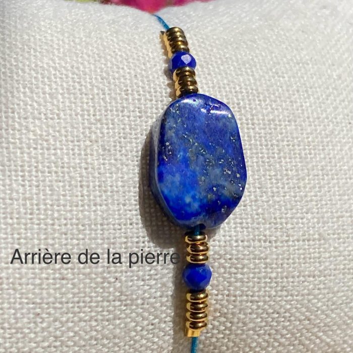 Bracelet bohème en lapis-lazuli (perle centrale rectangulaire et 2 petites perles facettées), avec des apprêts acier doré, posé sur un coussin beige