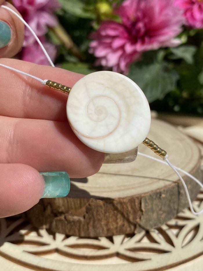 Zoom sur les spirales de l’œil de Shiva blanc d'un bracelet bohème sur fil jade blanc avec perles dorées