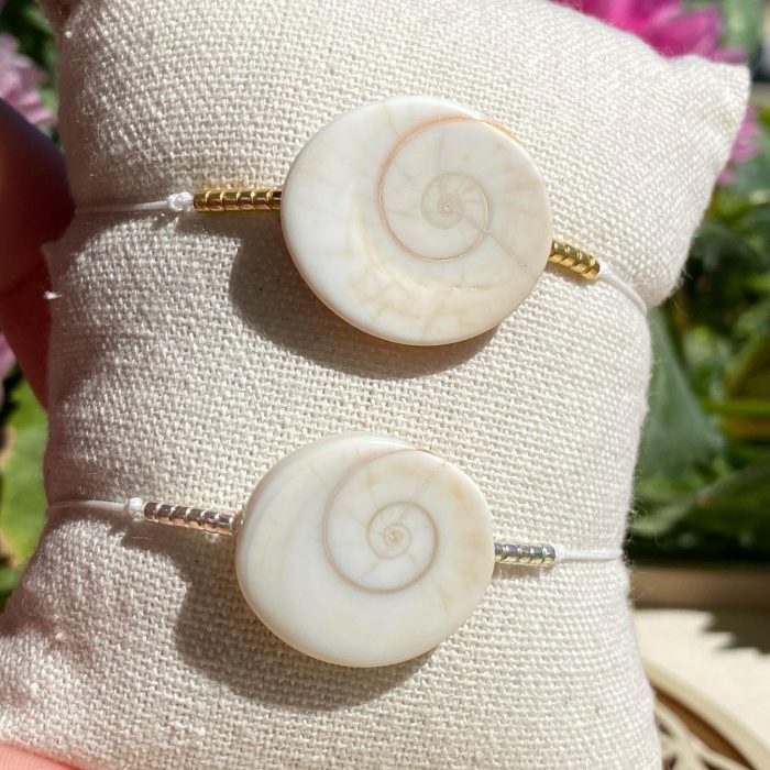 Zoom sur les spirales de l’œil de Shiva, des 2 bracelets bohème sur fil jade blanc avec perles dorées et argentées
