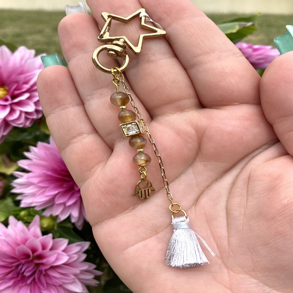 Porte-clé en agate avec pompon gris suspendu par une chaîne et une breloque main de fatma doré, fait main