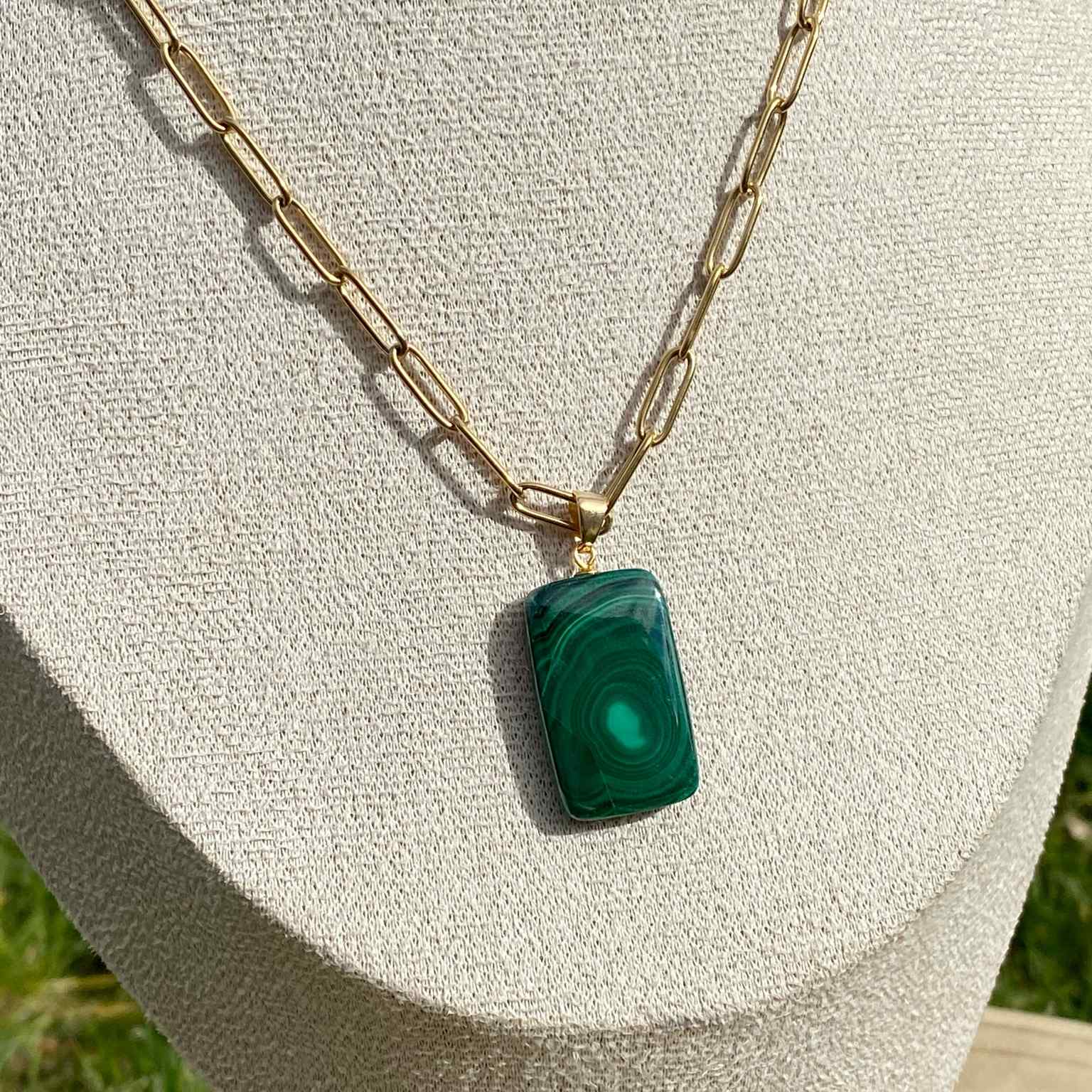 Pendentif en malachite naturelle sur chaîne à mailles rectangulaires en acier inoxydable doré. Pierre reliée au chakra du coeur : guérison émotionnelle et transformation, aux motifs verts uniques. Bijou élégant et énergétique Les Merveilles by Pauline.