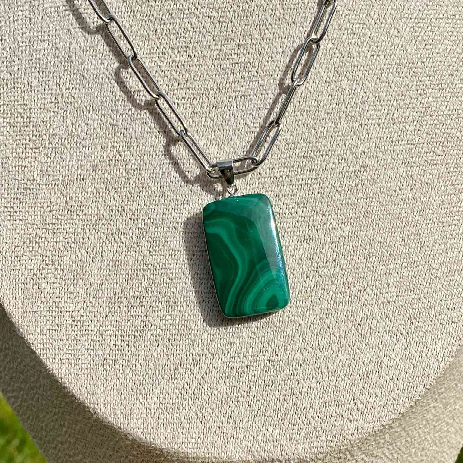 Pendentif en malachite naturelle sur chaîne à mailles rectangulaires en acier inoxydable doré. Pierre reliée au chakra du coeur : guérison émotionnelle et transformation, aux motifs verts uniques. Bijou élégant et énergétique Les Merveilles by Pauline.