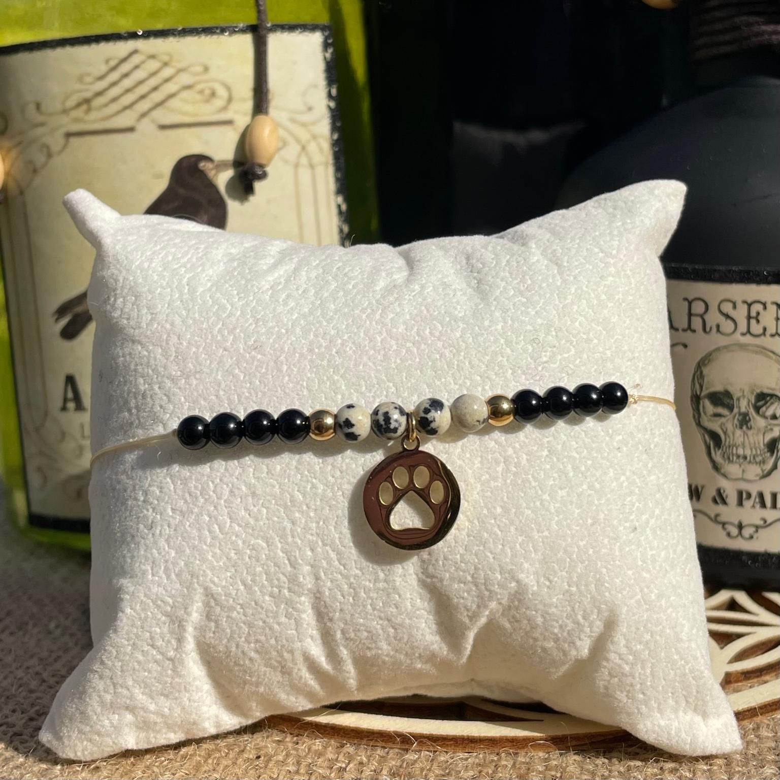 Bracelet Cruella en jaspe dalmatien et onyx avec breloque patte de chien dorée, bijou contrasté et audacieux en pierres naturelles fait main Les Merveilles by Pauline. Collection inspiré par les Méchants Disney.