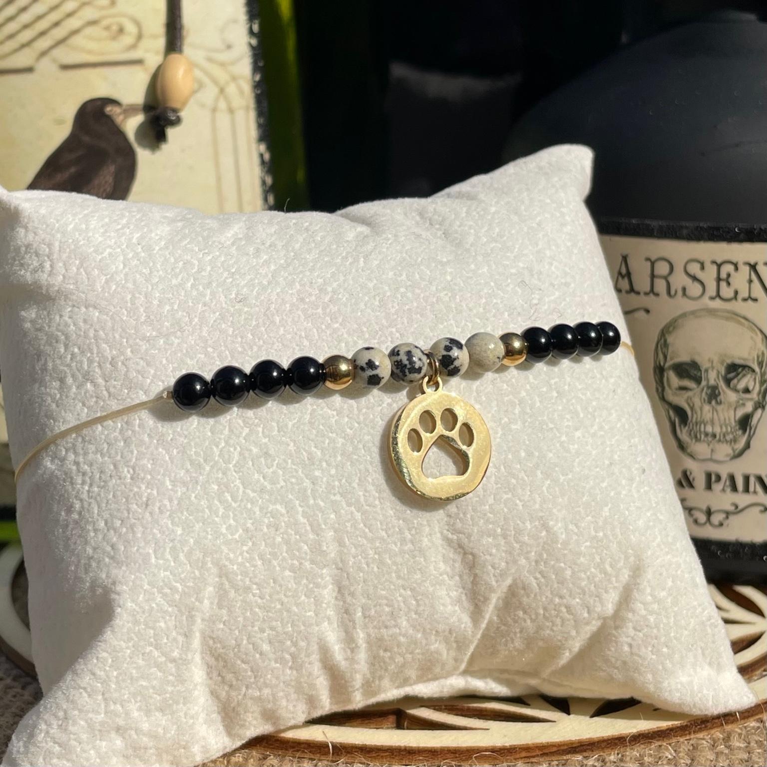 Bracelet Cruella en jaspe dalmatien et onyx avec breloque patte de chien dorée, bijou contrasté et audacieux en pierres naturelles fait main Les Merveilles by Pauline. Collection inspiré par les Méchants Disney.