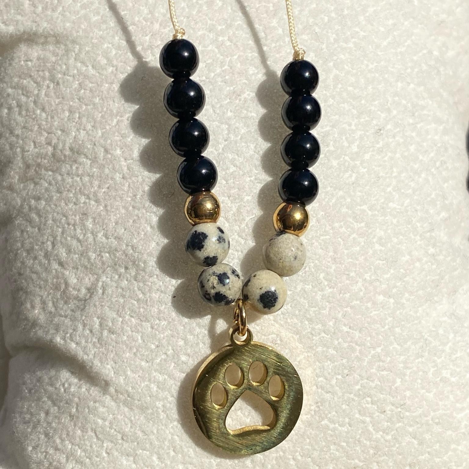 Bracelet Cruella en jaspe dalmatien et onyx avec breloque patte de chien dorée, bijou contrasté et audacieux en pierres naturelles fait main Les Merveilles by Pauline. Collection inspiré par les Méchants Disney.