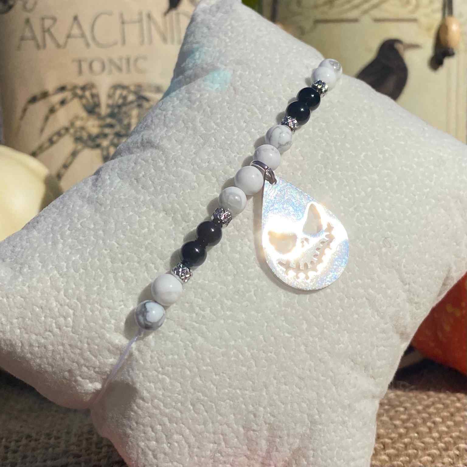 Bracelet Halloween Jack Skellington en pierres naturelles d’howlite et d’onyx noir, breloque goutte gravée en acier inoxydable, création inspirée de L’Étrange Noël de Monsieur Jack.