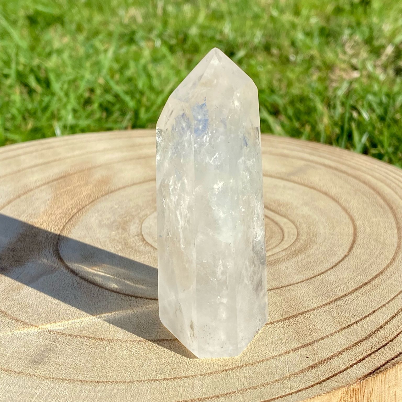 Pointe de cristal de roche naturelle avec inclusions laiteuses, pierre translucide aux reflets brumeux pour apaisement et pureté.